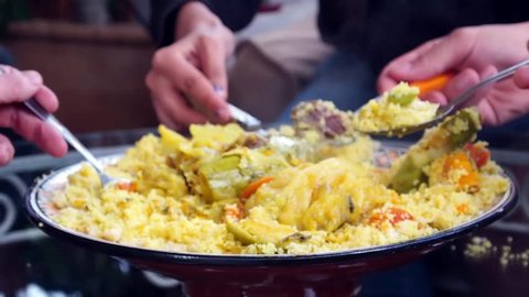 a Group of People Eating Traditional Moroccan Dish Couscous With Meat and Vegetables All Together From One Plate. Hands With Spoons. Family Dinner. Sharing. Close Up. Tangier, Morocco.
