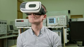 Young male student with glasses of virtual reality in the physical laboratory of the University. Man sees 3D model rotating head. future learning concept