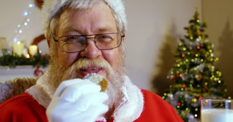 Santa claus relaxing on chair and having sweet food during christmas time at home 4k