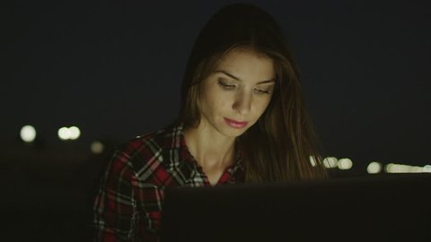 Girl using laptop on the beach at night
