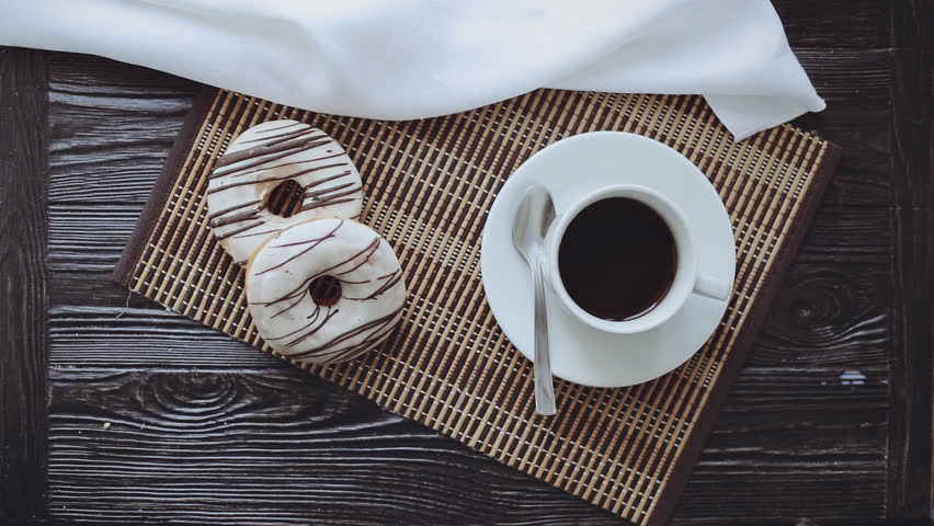 Man Pouring Milk into Coffee, Two Donuts on a Black Wooden Table, Top view