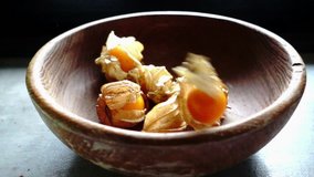 Cape gooseberry drop into wooden bowl, slow motion