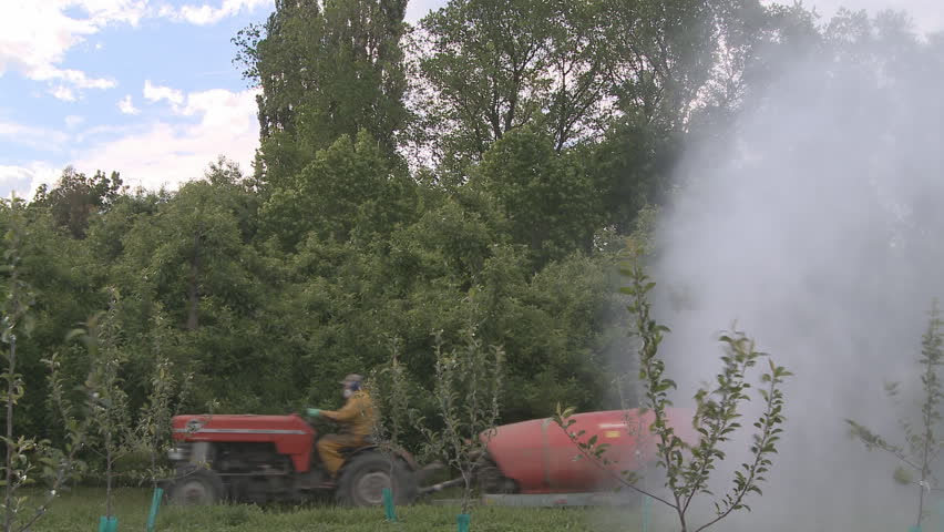 A sprayer applying pesticides to an apple orchard