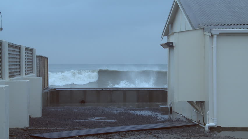 Seawater pours into the yard around a coastal property as a result of storm seas