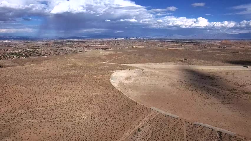 Aerial of desert landscape in far background showing downtown Las Vegas bird-eye view of dunes rocky environment located within greater Mojave Desert in state of Nevada county seat of Clark County 4k