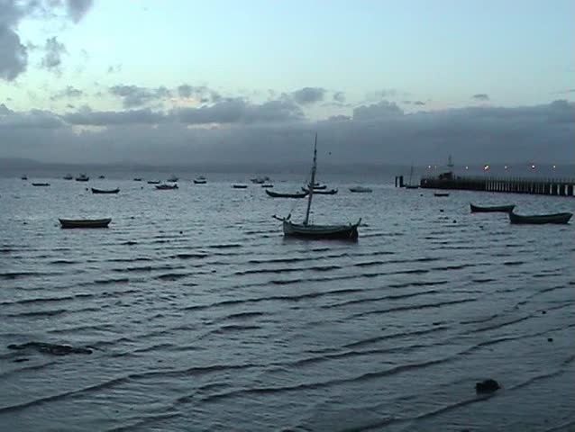 Old pier and surrounded by blue water and blue clouds.