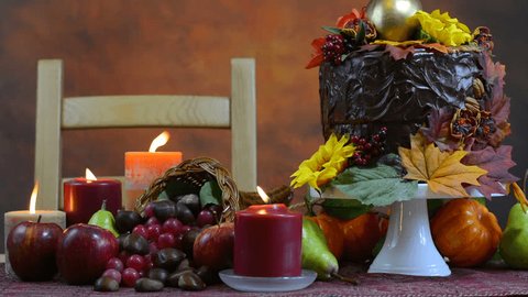 Beautiful Thanksgiving Fall table setting with Autumn theme chocolate cake, cornucopia and candles, close up static.
