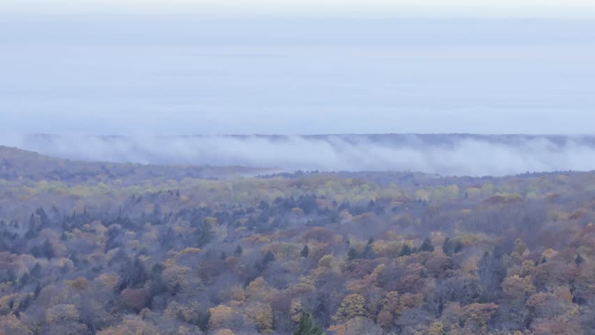 Telephoto Shot of Clouds and Fog Covering Lake Superior and Rolling Over Fall Michigan Trees 4K UHD Timelapse