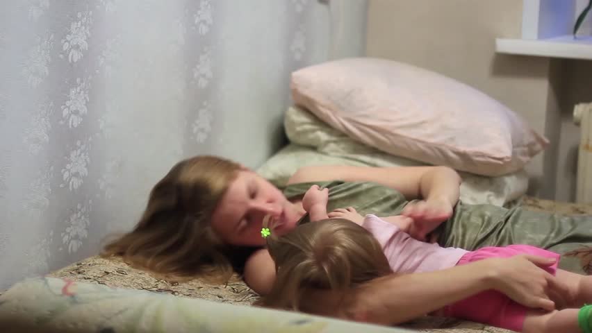 mother playing with baby on bed