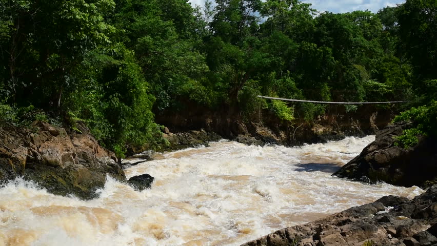 Tourist at the rope bridge above tempestuous wild water, Don Det, Laos