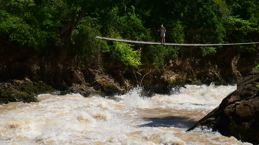 Tourist at the rope bridge above tempestuous wild water, Don Det, Laos