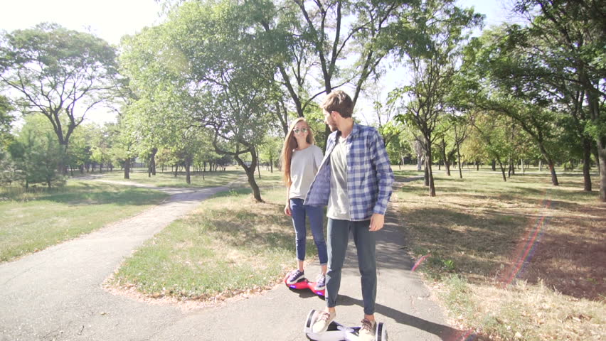 Young couple ridding hoverboard with holding hands. Wide shot Royalty-Free Stock Footage #21332191
