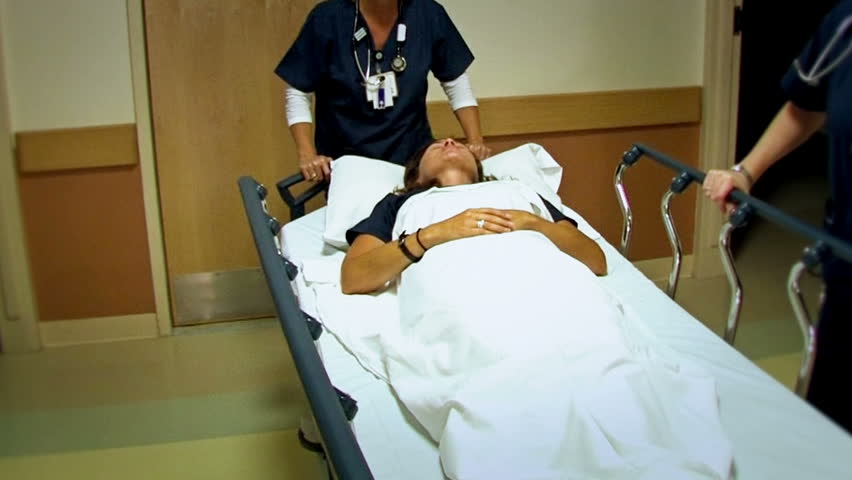 Woman patient on stretcher in a hospital's hallway. Royalty-Free Stock Footage #2134118