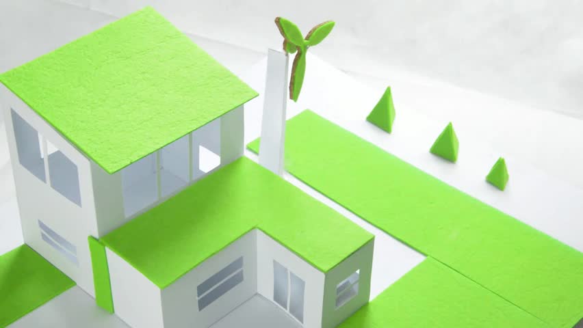The architectural model of the house and woman hand rotating the windmill.. The concept of electricity cheaper and more environmentally friendly energy. Eco house. Lower electricity costs.
