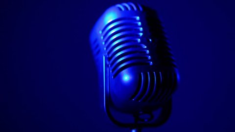 Retro microphone spins lit by colorful light at dark background Stock Video