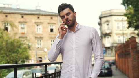 Handsome man standing in the city and chatting on cellphone
