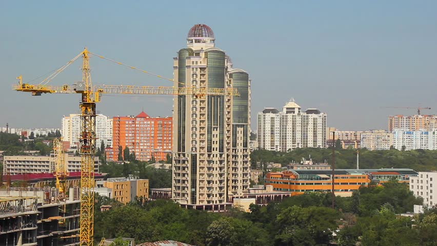 Panorama of Odessa city, Ukraine. Yellow tower crane, construction sites, modern high-rise buildings, public buildings and green areas on clear blue sky background. 