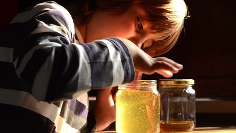 Child eats honey from jar