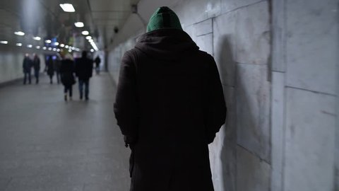 Suspicious hooded man goes through the underpass