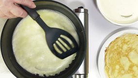 Female hands baking pancake into a frying pan