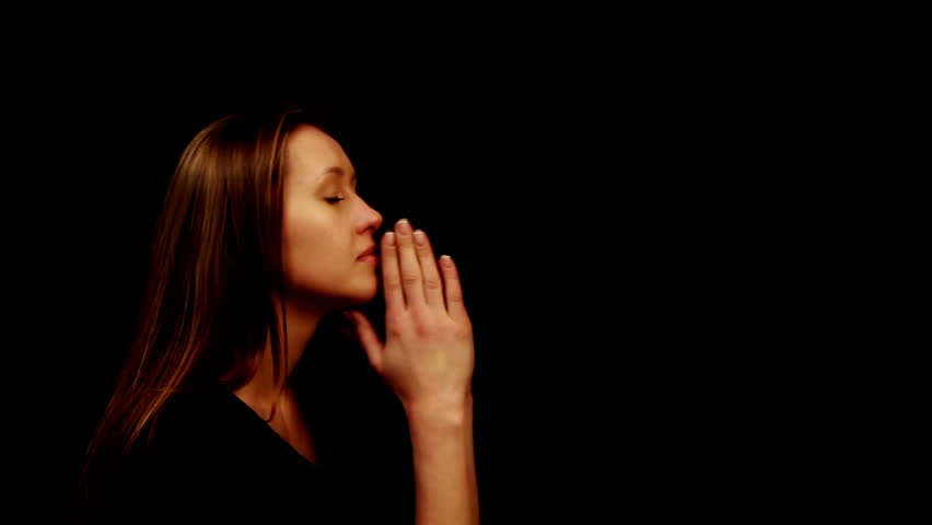 woman praying on a black background