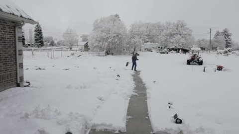 Man shoveling snow off home sidewalk during late winter storm. Fast motion time lapse. 
