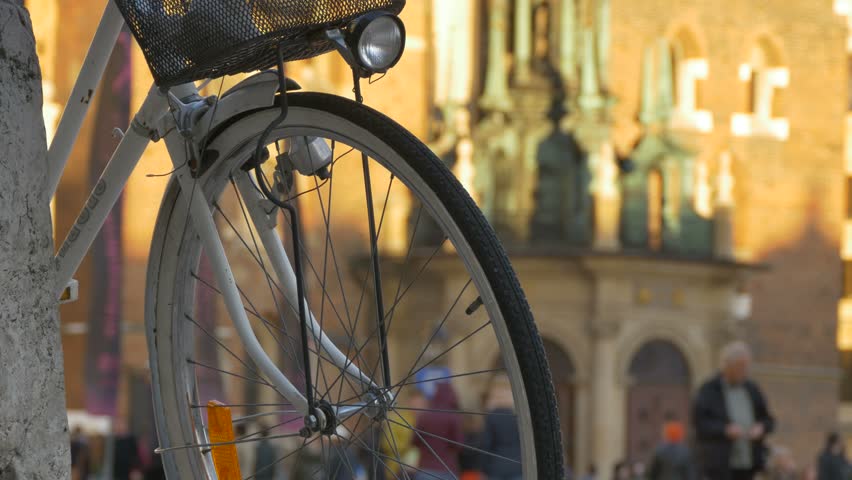 Close-up shot of bicycle wheel and headlight lantern, in the city afternoon.