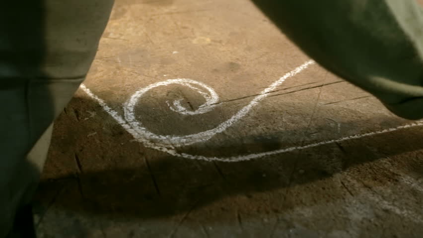Close-up hand of a young blacksmith who draws a chalk sketch on the table