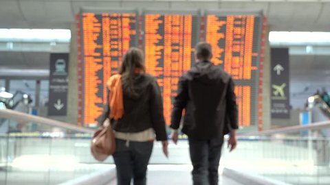 Woman and man holding passports getting closer to airplane flight timetable schedule chart screen, looking for arrivals and departures to the perfect holiday destination