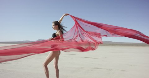 Girl with a fabric walking and dancing in the desert