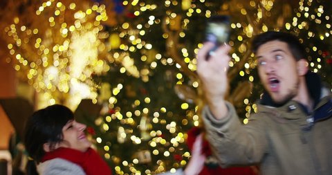 a boy with blue eyes at Christmas take a picture in front of the Christmas tree in a shopping center. concept of celebration, happiness and user friendly technology. live streaming tecnology.