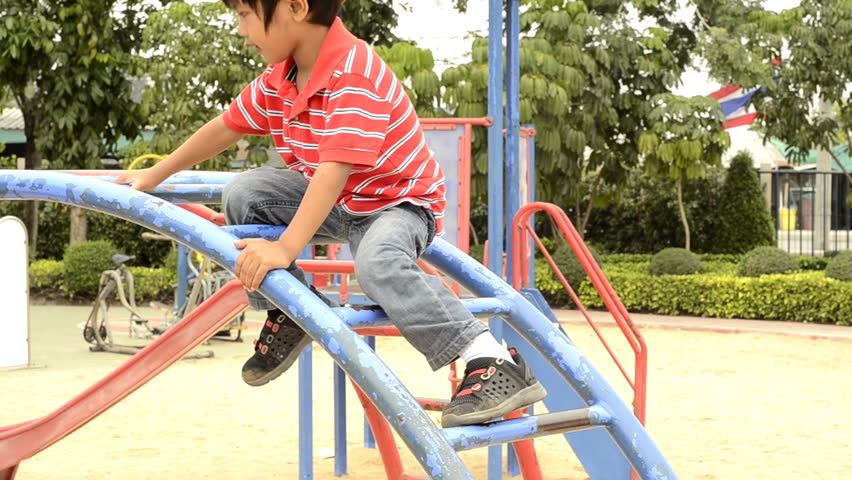 Young boy climbing on a climbing frame in a playground.