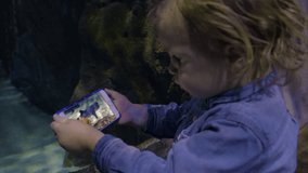 Closeup Of Little Boy Taking A Video Of Two Sharks In Aquarium 