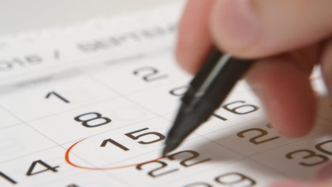 Signing a day on a calendar by red pen