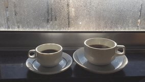 Cup of coffee or tea on fogged or frozen window background. Closeup image, Clip 160319452 Full HD video footage