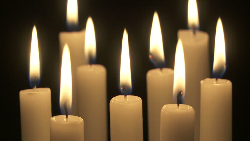 Wide shot of a group of candles burning in the dark