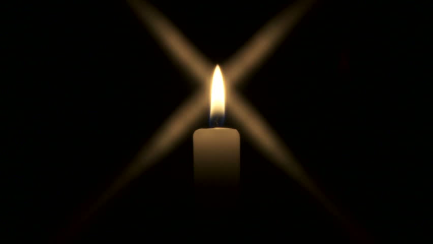 Medium shot of candle burning in the dark