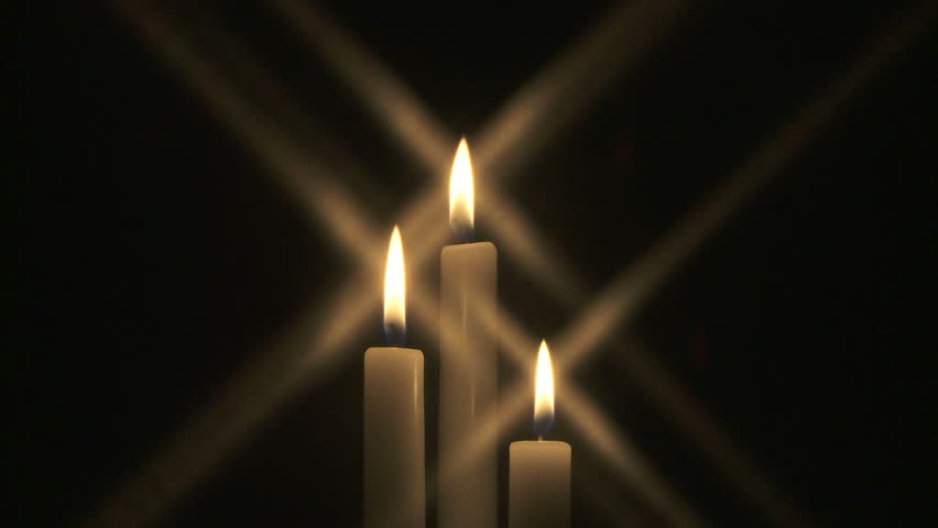 Group of three candles burning in the dark