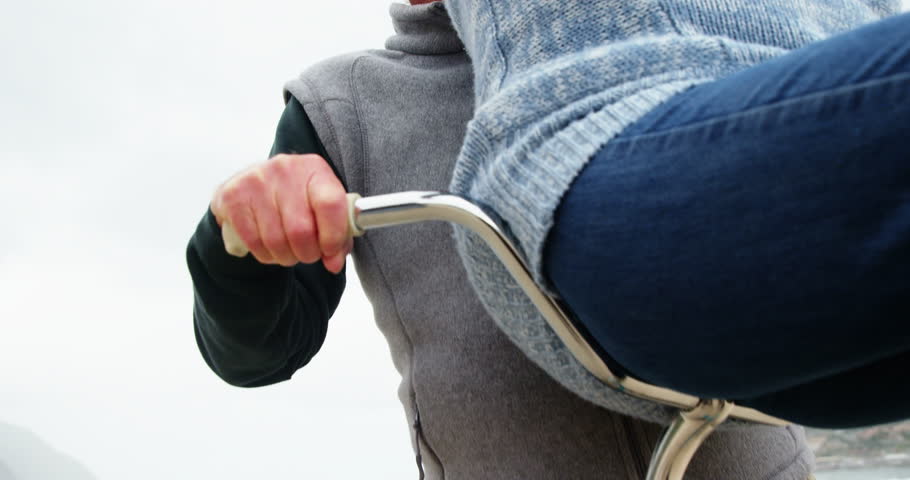 Happy senior couple sitting on bicycle with arms outstretched on beach