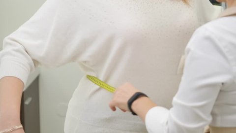 Doctor measuring obese woman waist body fat. Obesity and weight loss.