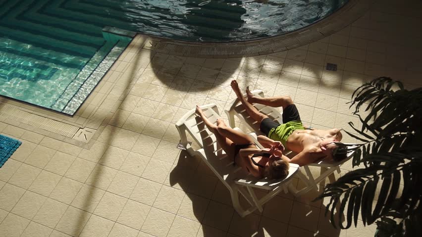Couple chatting on sunbeds near pool
