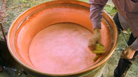 Man prepares and washes cauldron for baking domestic brandy