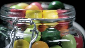 Colorful candies and chewing gum in glass jar. video rotation