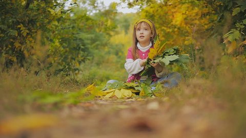 little girl throws autumn leaves. Happy child. Slow-motion