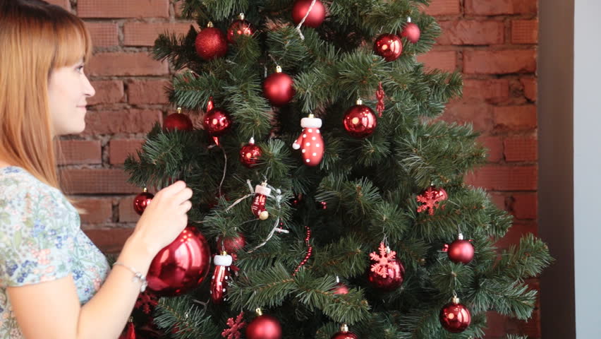 Smiling woman decorating Christmas tree at home
