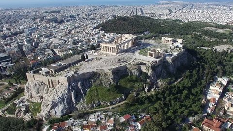 Aerial drone bird-eye view moving around front of the Acropolis of Athens ancient citadel located on rocky outcrop showing Parthenon very famous tourist attraction in Europe Greece European visit 4k