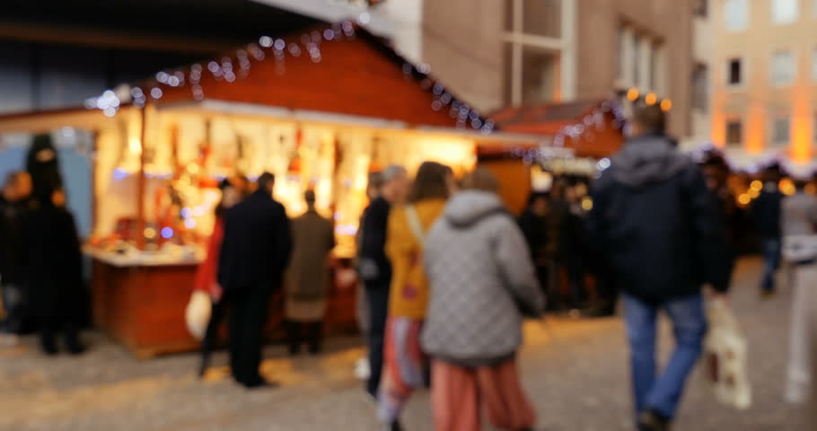 People shopping at Christmas Market defocused view of friends, man with dog and families walking and admiring the beauty of the holiday
