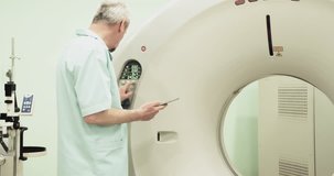 Doctor presses settings button of CT MRI scanner 4k video. Medical equipment: computed tomography ma?hine in diagnostic clinic