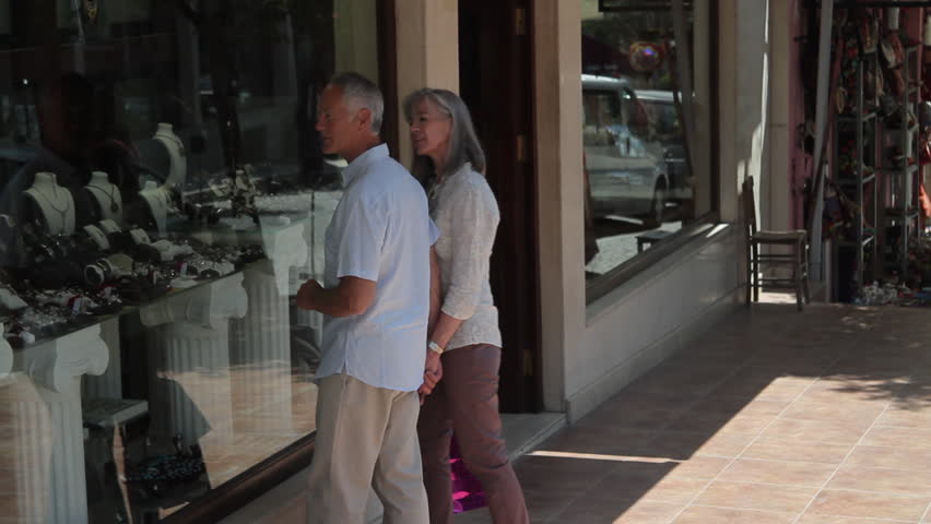 Couple looking at shop window and walk with shopping bags