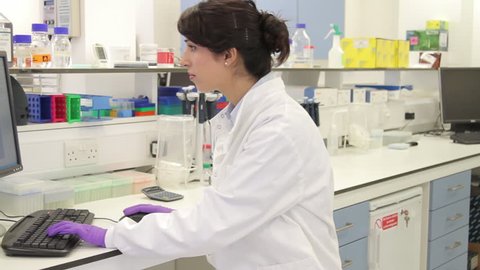 Female scientist working on computer and looks at screen in laboratory